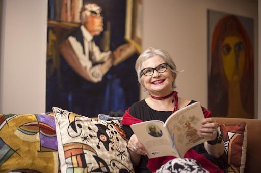 Escritora em sua casa, cercada pela própria biblioteca.